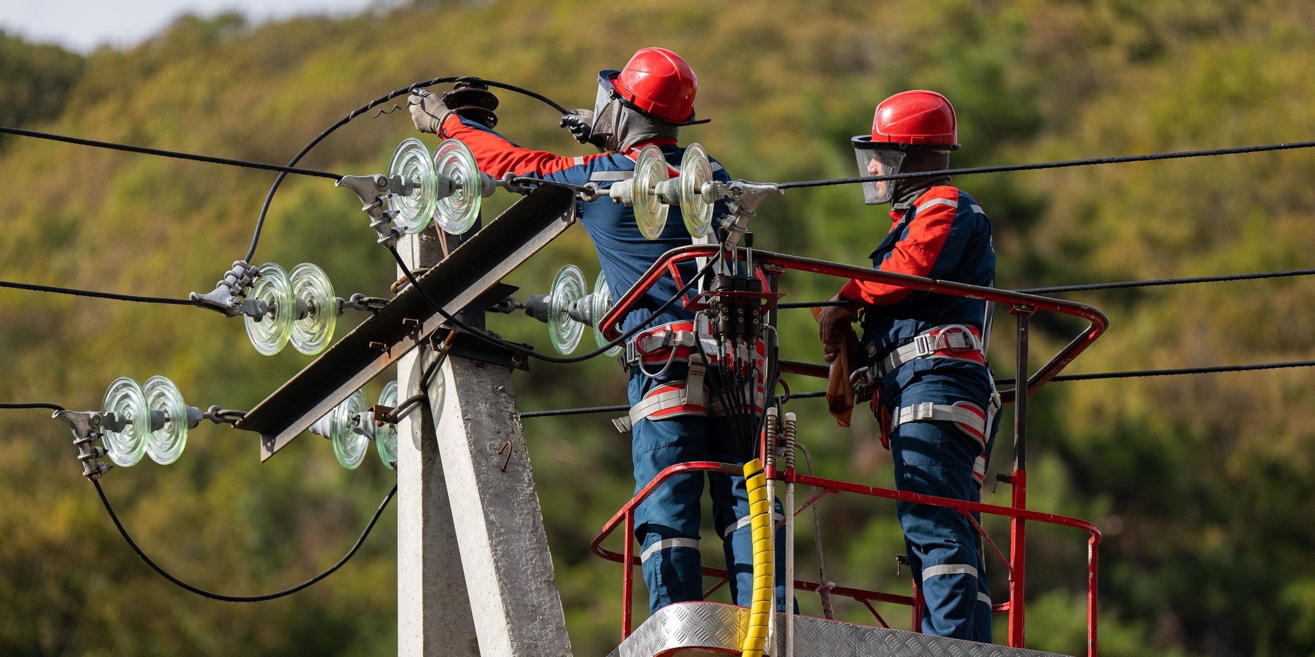 Dos electricistas trabajan en altura